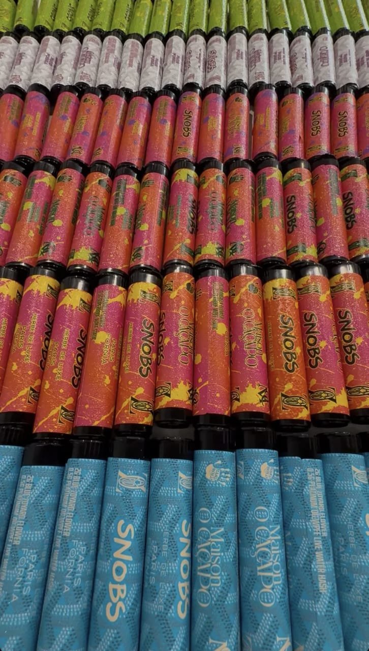 Maison O Caçapo and SNOBS luxury pre-roll doob tubes featuring blue Zoyard chevron pattern and orange splatter custom packaging.